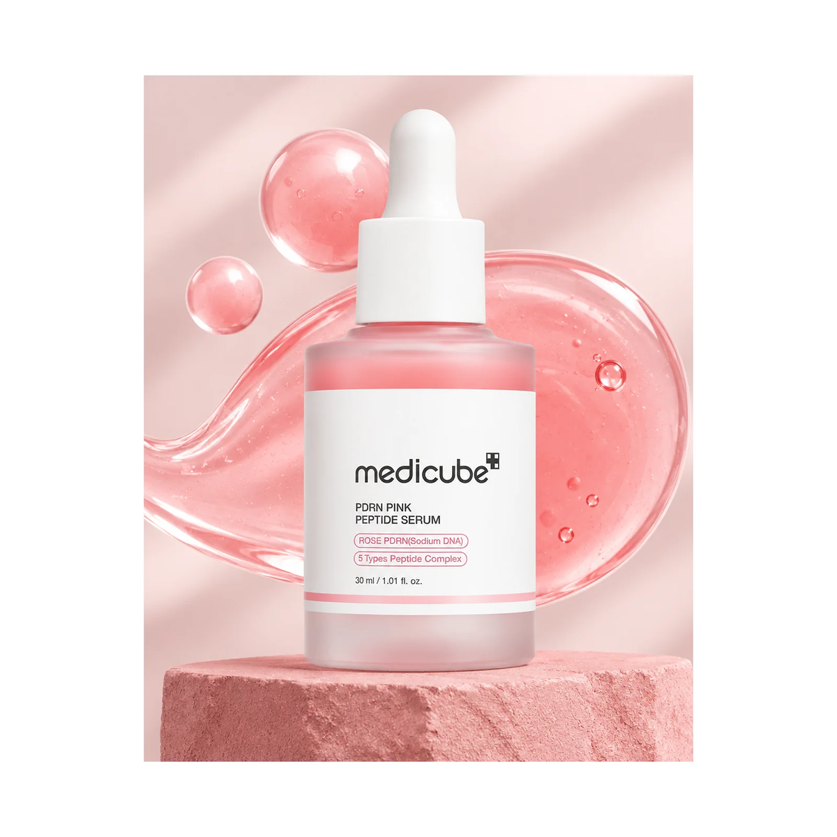 Sérum Medicube PDRN Pink Peptide mis en scène sur un socle rose poudré avec texture de gel rose